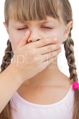 Little blond girl with her hand on her mouth with her eyes close