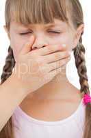 Little blond girl with her hand on her mouth with her eyes close