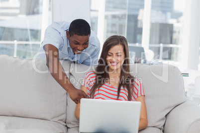 Cheerful creative designer pointing at a laptop