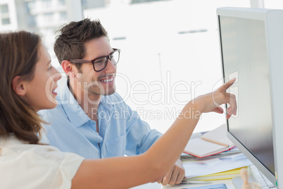 Attractive photo editor pointing at the computer screen