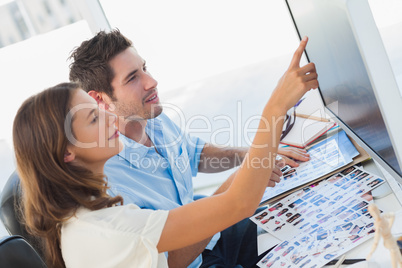 Young photo editors pointing at a computer screen