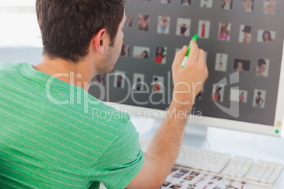 Photo editor pointing at his screen with a green marker
