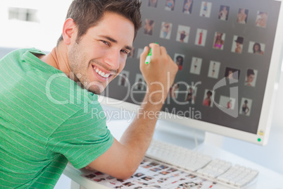 Cheerful photo editor pointing at his screen