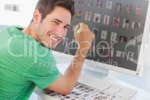 Cheerful photo editor pointing at his screen