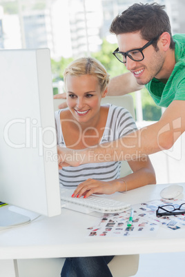 Cheerful photo editor pointing at a computer