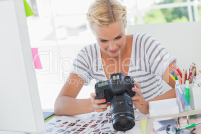 Blonde photo editor looking at a digital camera