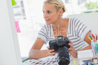 Pretty photo editor looking at a digital camera