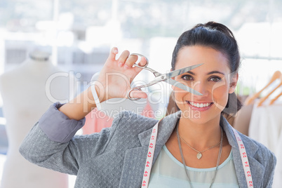 Attractive designer holding scissors in front of her face