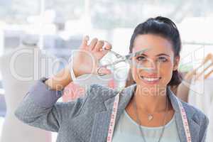 Attractive designer holding scissors in front of her face