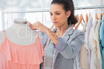 Attractive designer adjusting,dress on a mannequin