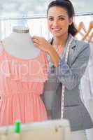 Smiling fashion designer adjusting dress