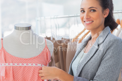 Smiling fashion designer measuring dress