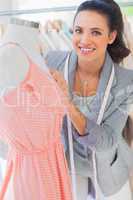 Happy designer fixing dress on a mannequin