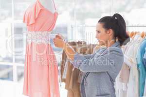 Pretty fashion designer measuring dress on a mannequin