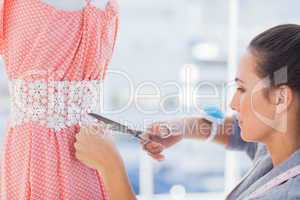 Fashion designer cutting dress