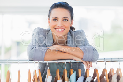 Attractive fashion designer leaning on clothes