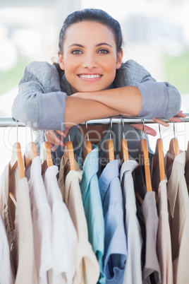 Pretty fashion designer leaning on clothes