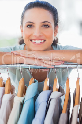 Portrait of a designer leaning on clothes