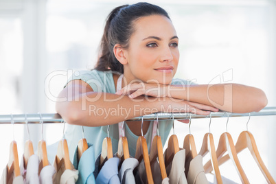 Beautiful fashion designer leaning on clothes