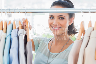 Smiling fashion designer looking at clothes