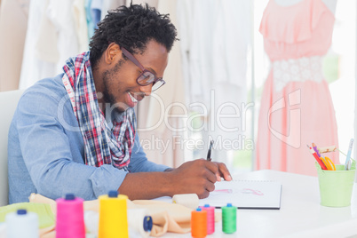 Attractive fashion designer sitting at his desk drawing