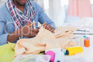 Fashion designer cutting textile