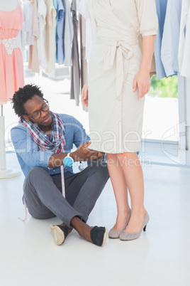Fashion designer sitting on the floor adjusting dress