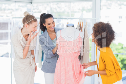 Attractive fashion designers looking at a dress