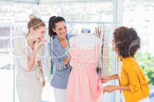 Attractive fashion designers looking at a dress