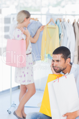 Desperate man being bored while his wife is shopping