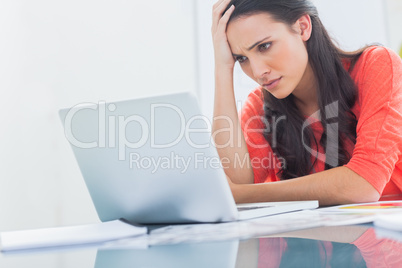 Confused designer looking at her laptop