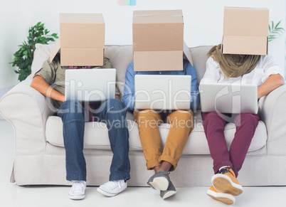 Designers working on laptops with boxes over their head