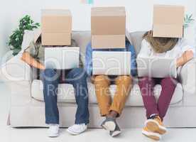Designers working on laptops with boxes over their head