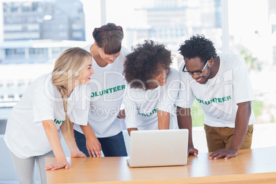 Smiling volunteers working together on a laptop