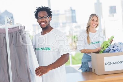 Pretty volunteers taking clothes out of a donation box