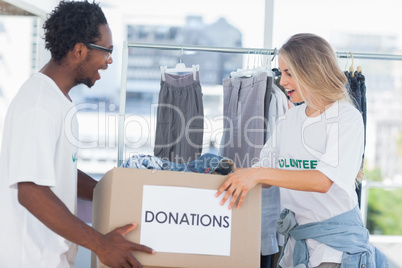 Cheerful volunteers looking at a donation box