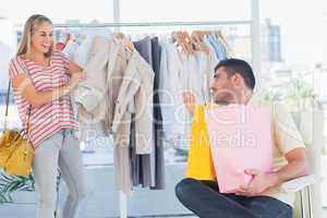 Depressed man looking at his shopaholic girlfriend