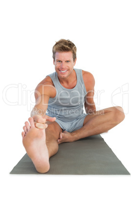 Cheerful man stretching his leg on the floor