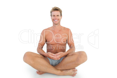 Cheerful man with eyes closed meditating on the floor