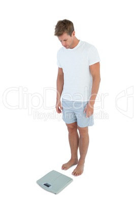 Athletic man looking at a weighing scale