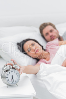 Tired woman turning off the alarm clock