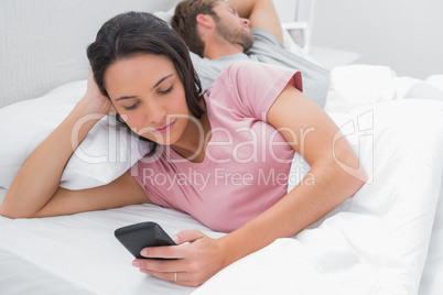 Woman texting while her partner is sleeping