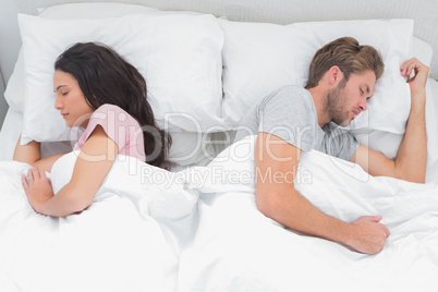 Couple sleeping back to back in their bed