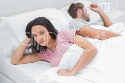 Woman thinking in her bed next to her sleeping husband