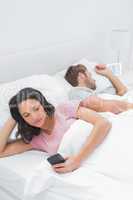 Woman text messaging in bed while her husband is sleeping