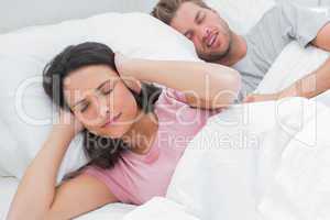 Woman covering ears while her husband is snoring