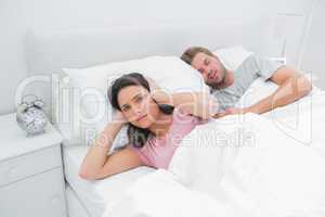 Snoring man is annoying his wife who tries to sleep