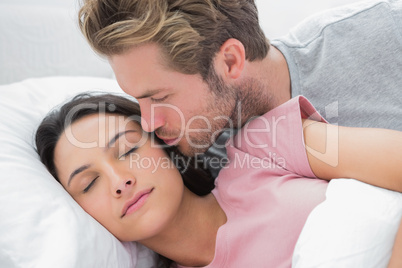 Man kissing his sleeping wife on the cheek
