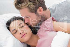Man kissing his sleeping wife on the cheek