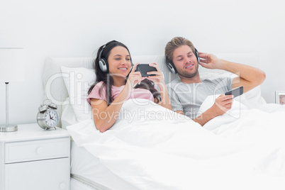 Couple listening to music in their bed with smartphones